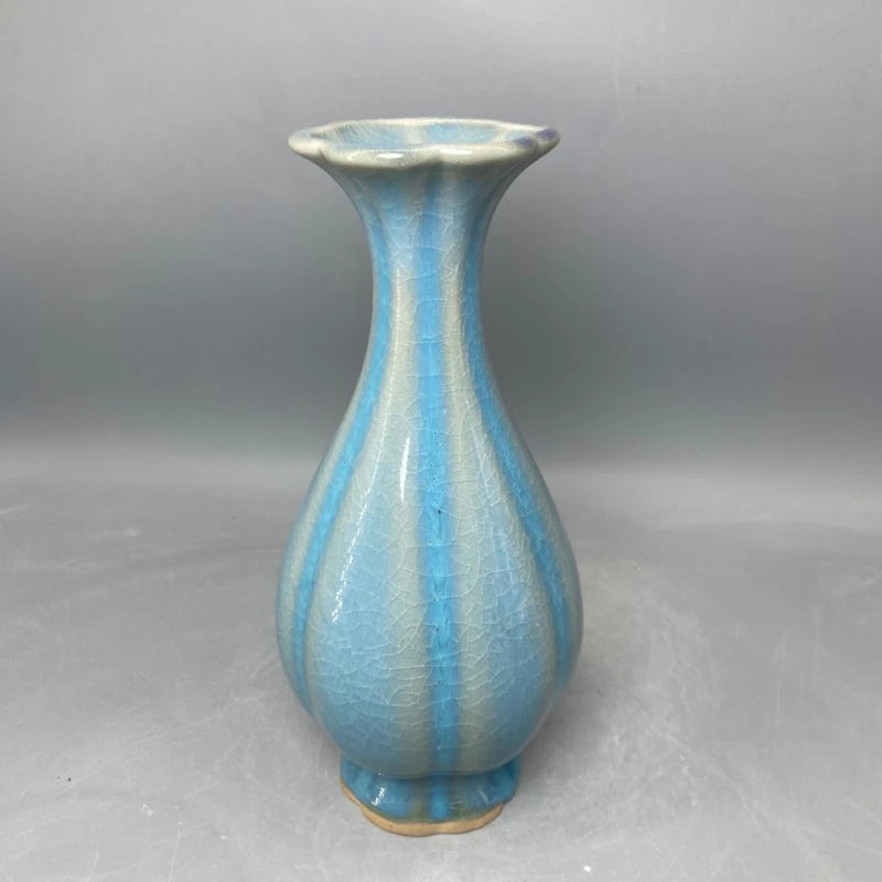 Un vase en céramique de forme élancée et allongée, avec un fini craquelé en nuances de bleu clair et foncé, créant un effet élégant et distinctif.
