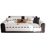 Le canapé est recouvert de coussins de style tribal beige et noir, avec des détails de style barbelé, créant une ambiance moderne et épurée.