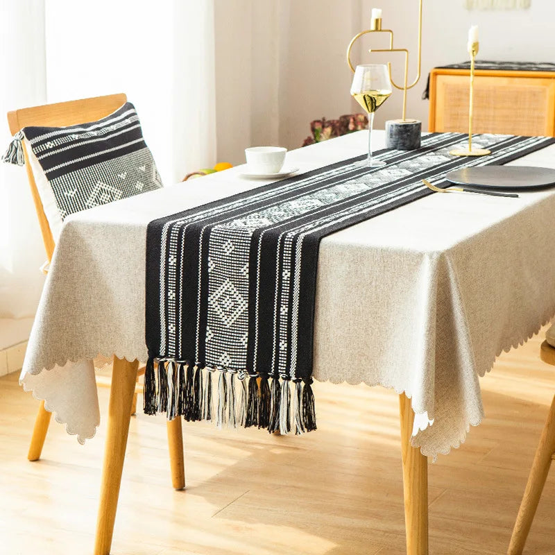 Une table élégante avec une nappe beige ornée de motifs géométriques noirs et blancs, ainsi que des accessoires de style nordique, créant une ambiance chaleureuse et raffinée dans cette salle à manger.