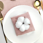 Un beau bouquet de coton blanc disposé élégamment sur un linge rose pâle, entouré d'ustensiles de cuisine dorés.