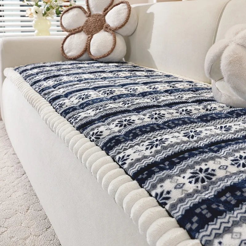 Couvre-lit en jacquard bleu marine et blanc avec motifs floraux élégants, posé sur un canapé moelleux dans un intérieur confortable.