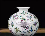 Vase en porcelaine blanc orné de motifs floraux colorés et d'un oiseau décoratif.