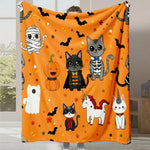 Une couverture moelleuse décorée de motifs de chats mignons et d'autres éléments d'Halloween, dans des tons oranges et noirs festifs.