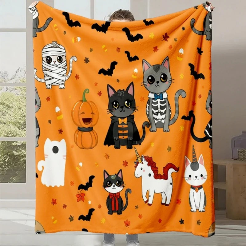 Une couverture moelleuse décorée de motifs de chats mignons et d'autres éléments d'Halloween, dans des tons oranges et noirs festifs.