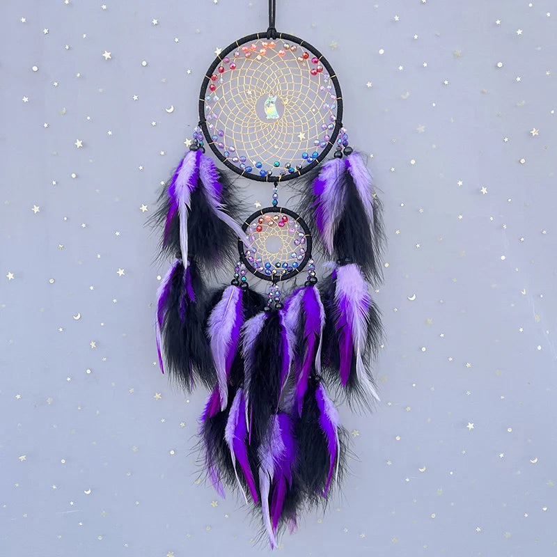 Un capteur de rêves coloré et orné de plumes pourpres et noires suspendu sur un fond étoilé.