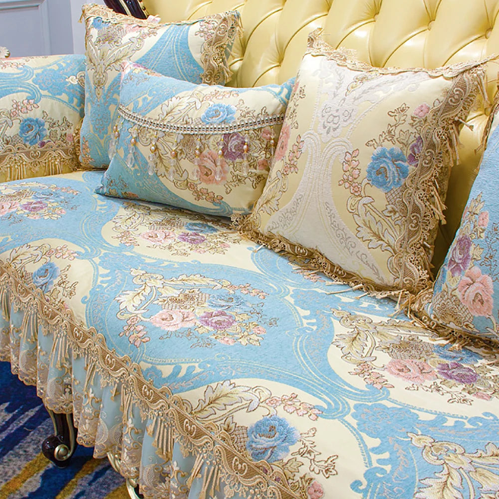 Élégant canapé capitonné avec des motifs floraux bleus et dorés, orné de coussins décoratifs aux designs vintages sophistiqués.