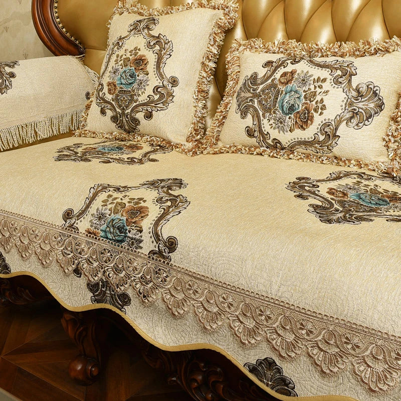 Couverture de lit et coussins ornés de motifs floraux et de motifs décoratifs élégants sur un fond beige, créant une ambiance luxueuse et raffinée dans cette pièce.