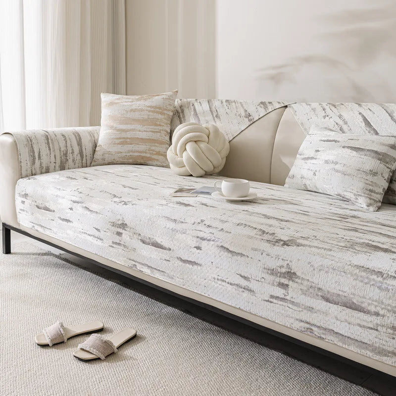 Un canapé moelleux avec des motifs abstrait sur le tissu, accompagné de coussins et d'un repose-pieds, créant une atmosphère sereine et relaxante dans le salon.