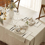 Une table élégamment dressée avec des fleurs fraîches, des verres et des couverts sur une nappe beige, créant une atmosphère chaleureuse et accueillante.