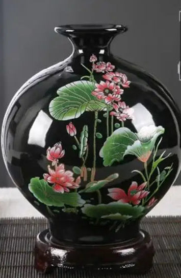 Un vase décoratif en porcelaine noire avec des fleurs roses peintes à la main.