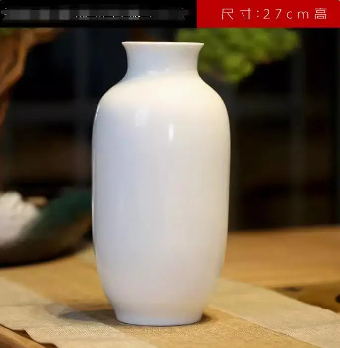 Vase en céramique blanc élégant et minimaliste, posé sur une surface en bois.