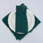 Élégante nappe de table blanche avec serviette en textile vert sombre sur une assiette blanche.