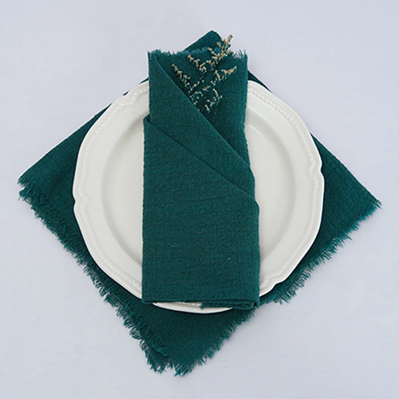 Élégante nappe de table blanche avec serviette en textile vert sombre sur une assiette blanche.