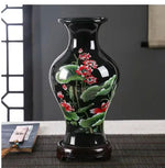 Vase décoratif en porcelaine noire avec des motifs de fleurs rouges et de feuilles vertes dans un style chinois traditionnel.