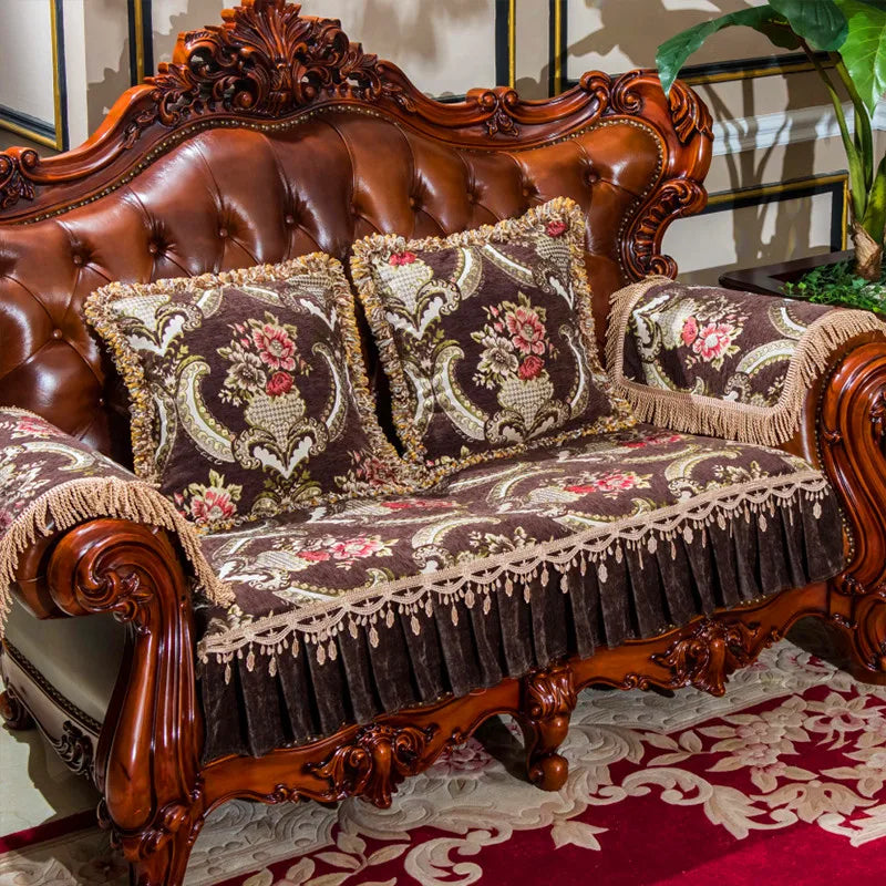 Un élégant canapé en cuir marron à l'allure classique, orné de magnifiques coussins floraux brodés et de franges élégantes, créant une atmosphère chaleureuse et invitante dans cette pièce d'intérieur.