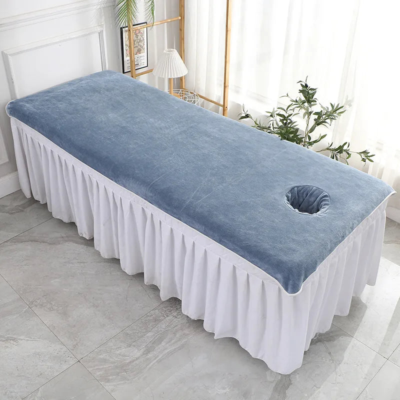 Un élégant lit de massage avec une couverture douce et un support pour coussin sous la tête.