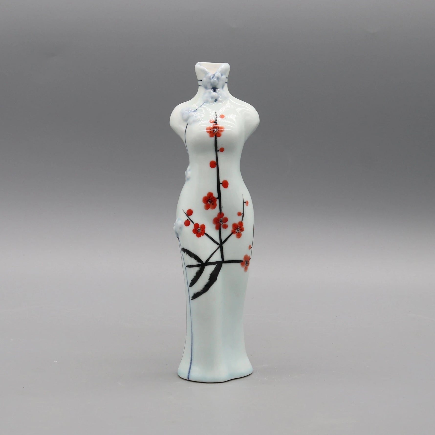 Cette céramique d'art japonaise représente un porte-bougie orné de fleurs de cerisier rouges stylisées sur un fond blanc nacré.