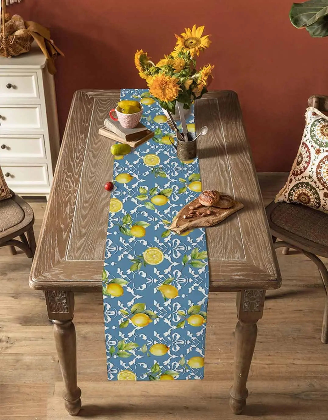 Une belle composition de tournesols jaunes, de citrons frais et d'un chemin de table avec un motif floral bleu et blanc, créant une atmosphère chaleureuse et accueillante dans cette pièce.