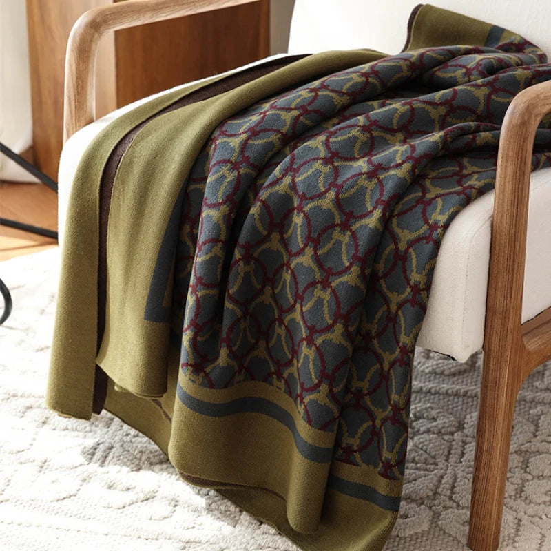 Plaid géométrique vert et gris plié sur fauteuil
