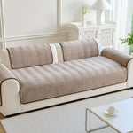 Un canapé élégant et moderne avec un motif chevron graphique dans des tons neutres, complété par un meuble d'appoint décoratif à côté.