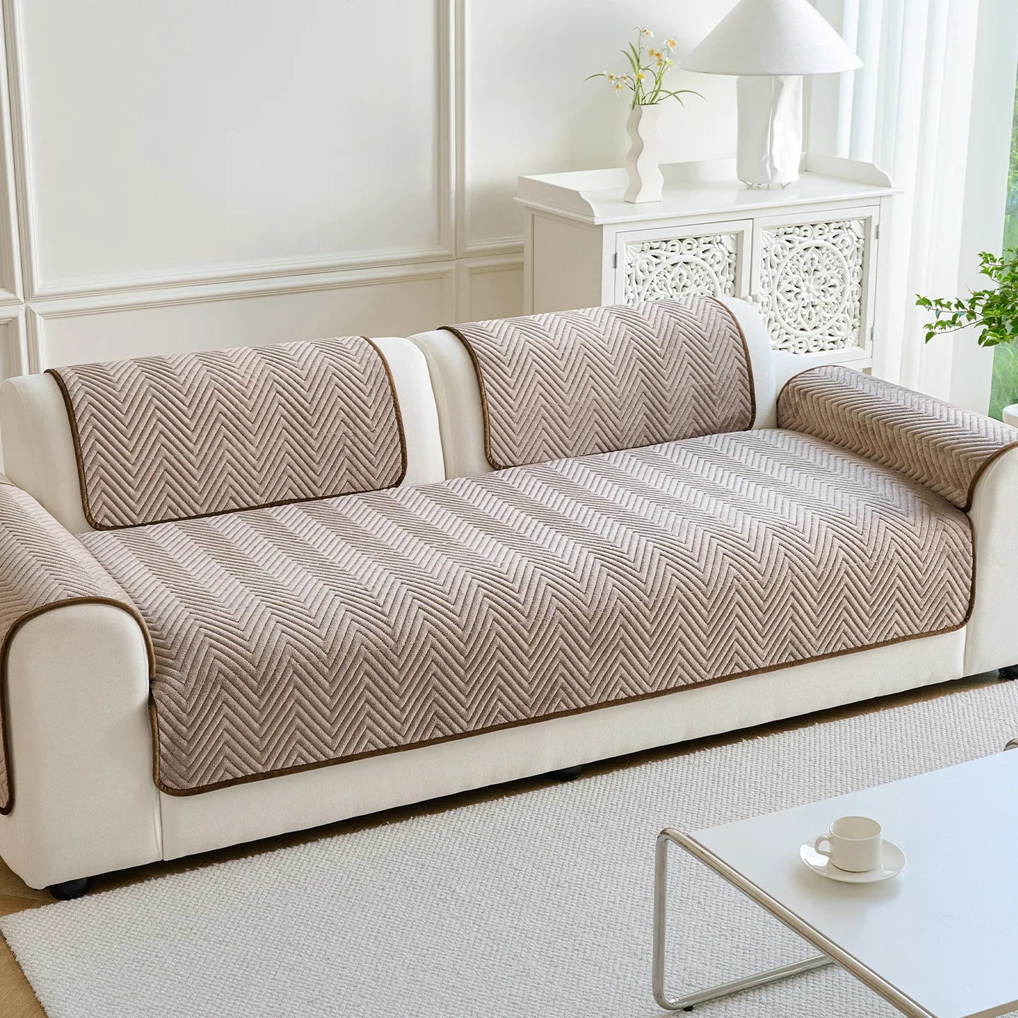 Un canapé élégant et moderne avec un motif chevron graphique dans des tons neutres, complété par un meuble d'appoint décoratif à côté.