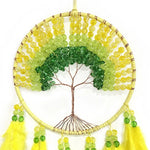 Arbre de la vie en forme de couronne fait de perles colorées vertes et jaunes, suspendu avec des franges pendantes.