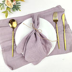 Une table de réception ornée de décorations élégantes, comprenant une assiette blanche, des couverts dorés et un linge de table de couleur lilas, formant un élégant cadre de repas.
