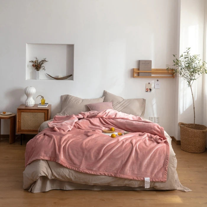 Une chambre à coucher aérée et élégante avec un lit douillet recouvert d'une couverture rose pastel, des éléments décoratifs naturels et un style épuré.