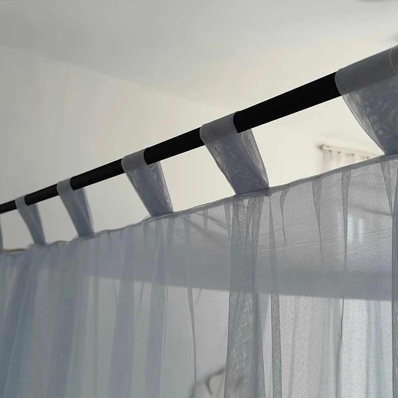 Des rideaux légers suspendus à des tringles sombres créent une ambiance élégante et apaisante dans la pièce.