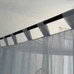 Des rideaux légers suspendus à des tringles sombres créent une ambiance élégante et apaisante dans la pièce.