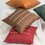 Des coussins carrés de différentes couleurs et motifs décoratifs sur un lit blanc.