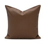 Coussin décoratif brun foncé avec un motif géométrique répétitif.