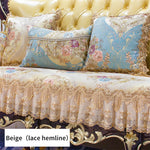 Un canapé élégant aux coussins et à la garniture de style baroque avec des motifs floraux et des franges dorées sur un fond beige.