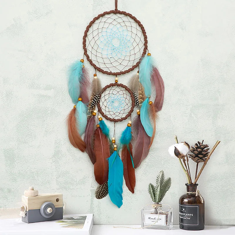 Attrape-rêves rustique décoré de plumes colorées, avec des perles et un design en forme d'araignée, suspendu sur un mur blanc avec des éléments décoratifs.