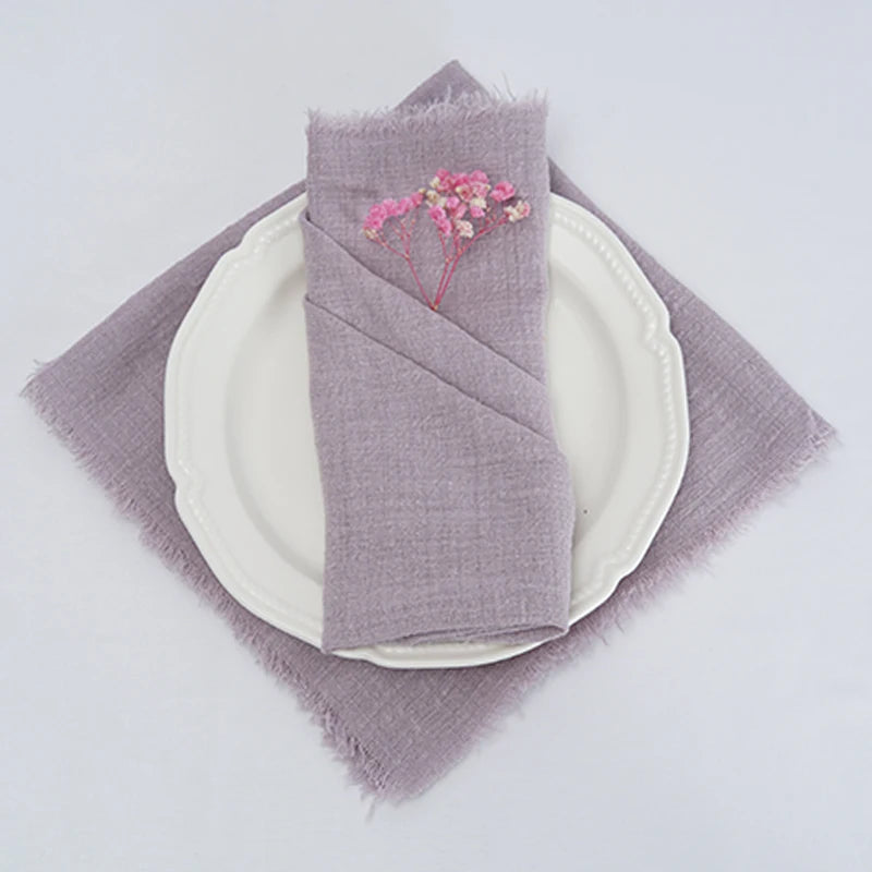 Assiette blanche avec serviette de table grise et fleurs décoratives sur un fond blanc.