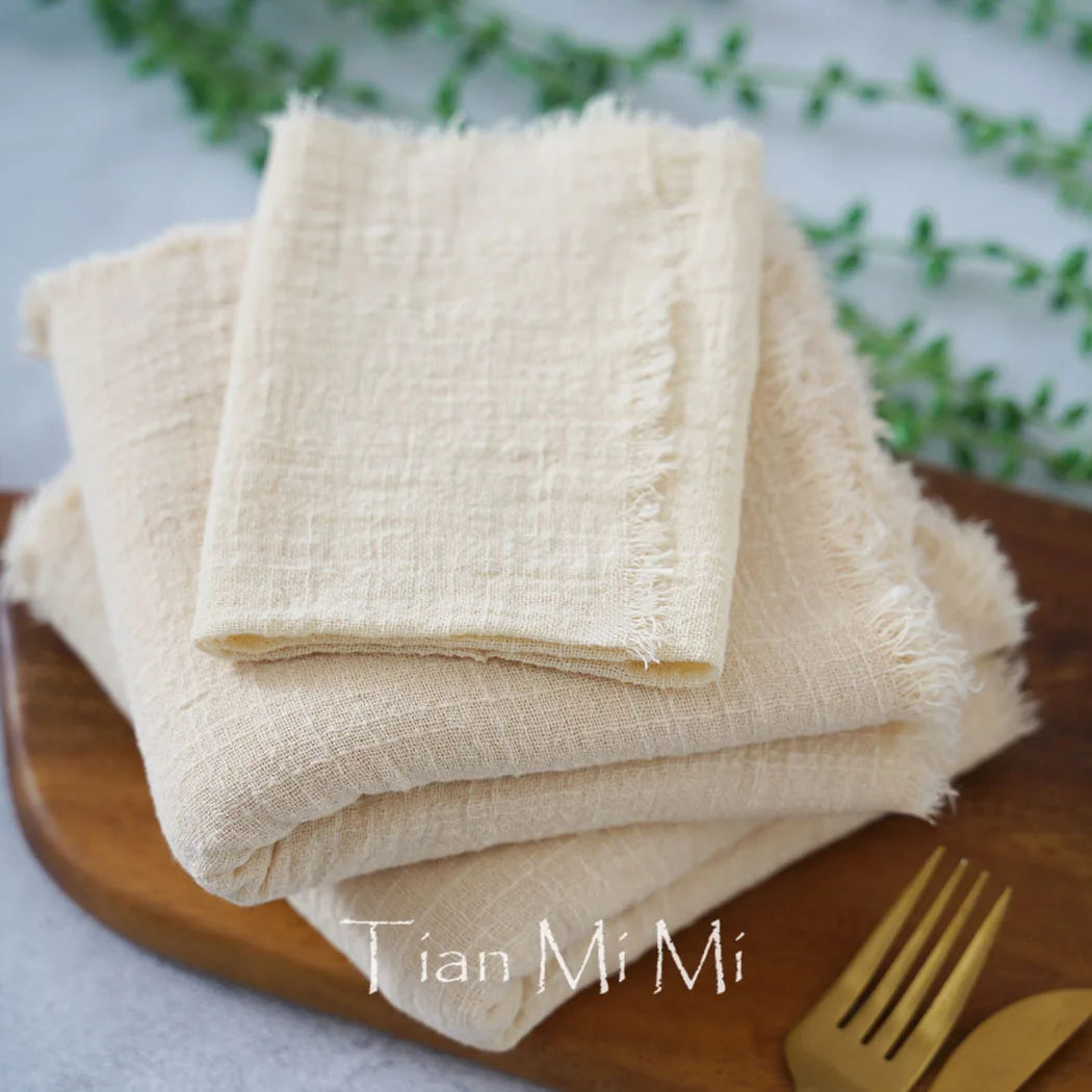 Serviettes de table en lin beige empilées sur une plaque en bois avec un titre manuscrit "Tian Mi Mi".