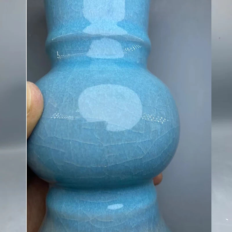 Un vase en céramique bleu turquoise avec des formes circulaires et des surfaces texturées.
