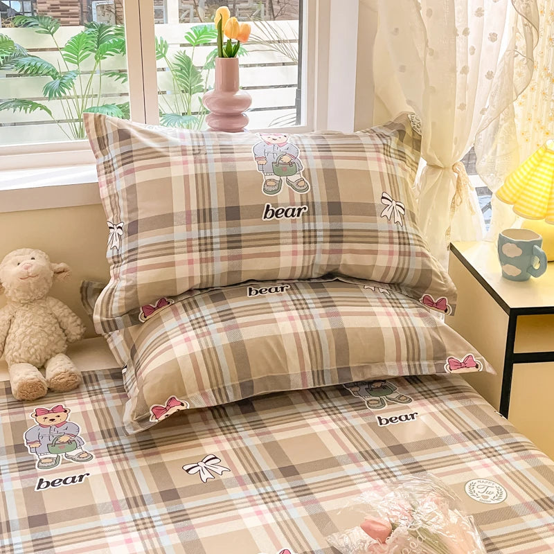 Un joli édredon à carreaux beige avec des ourses mignons imprimés, créant une ambiance douillette et confortable dans la chambre.