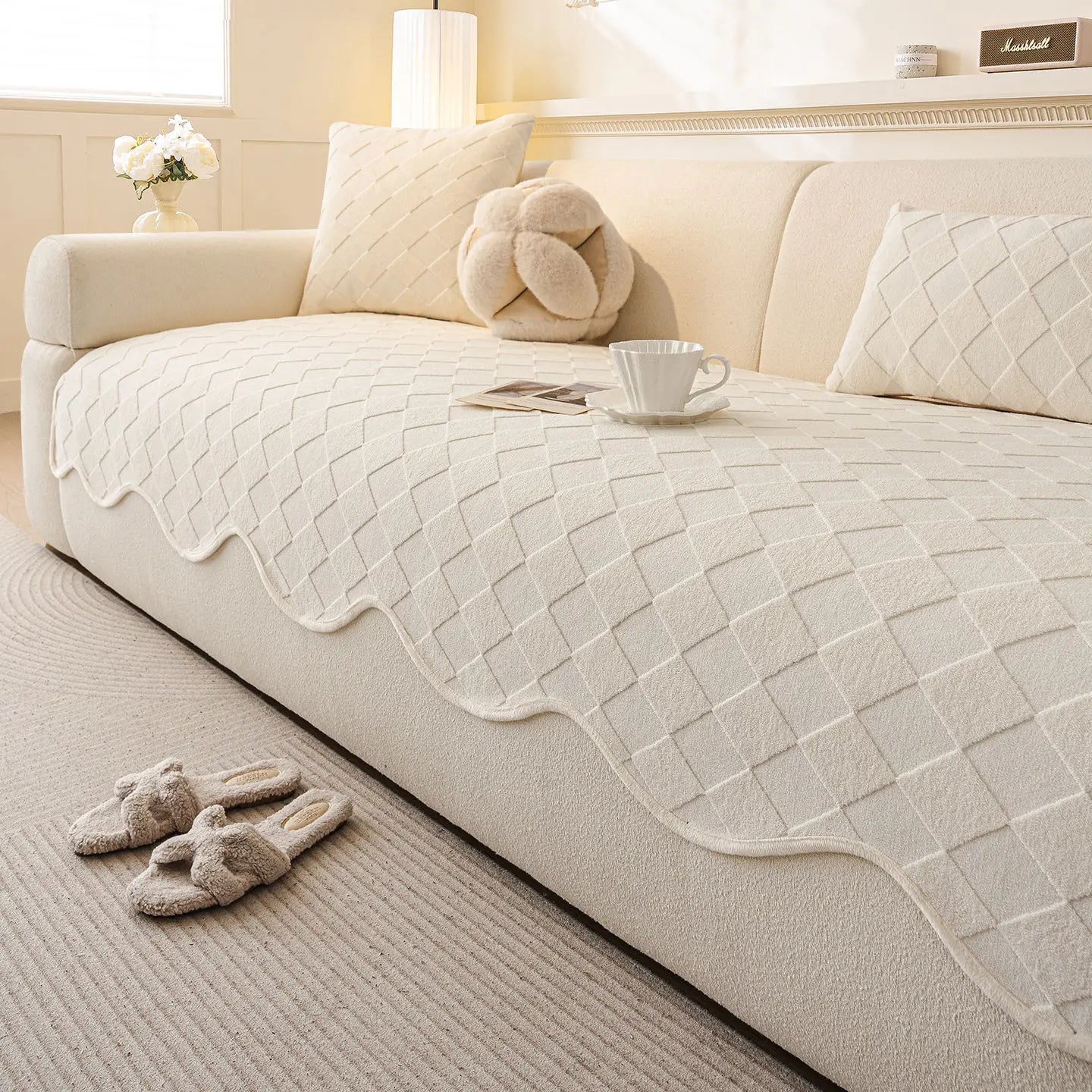 Une chambre confortable avec un grand canapé moelleux, des oreillers et une couverture à motif géométrique, ainsi que des jouets en peluche sur le sol, créant une atmosphère chaleureuse et accueillante.