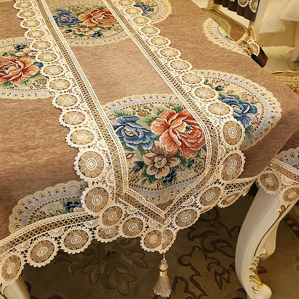 Cette image montre une belle nappe brodée aux motifs floraux colorés et entourée d'une dentelle blanche délicate, créant une atmosphère chaleureuse et élégante.