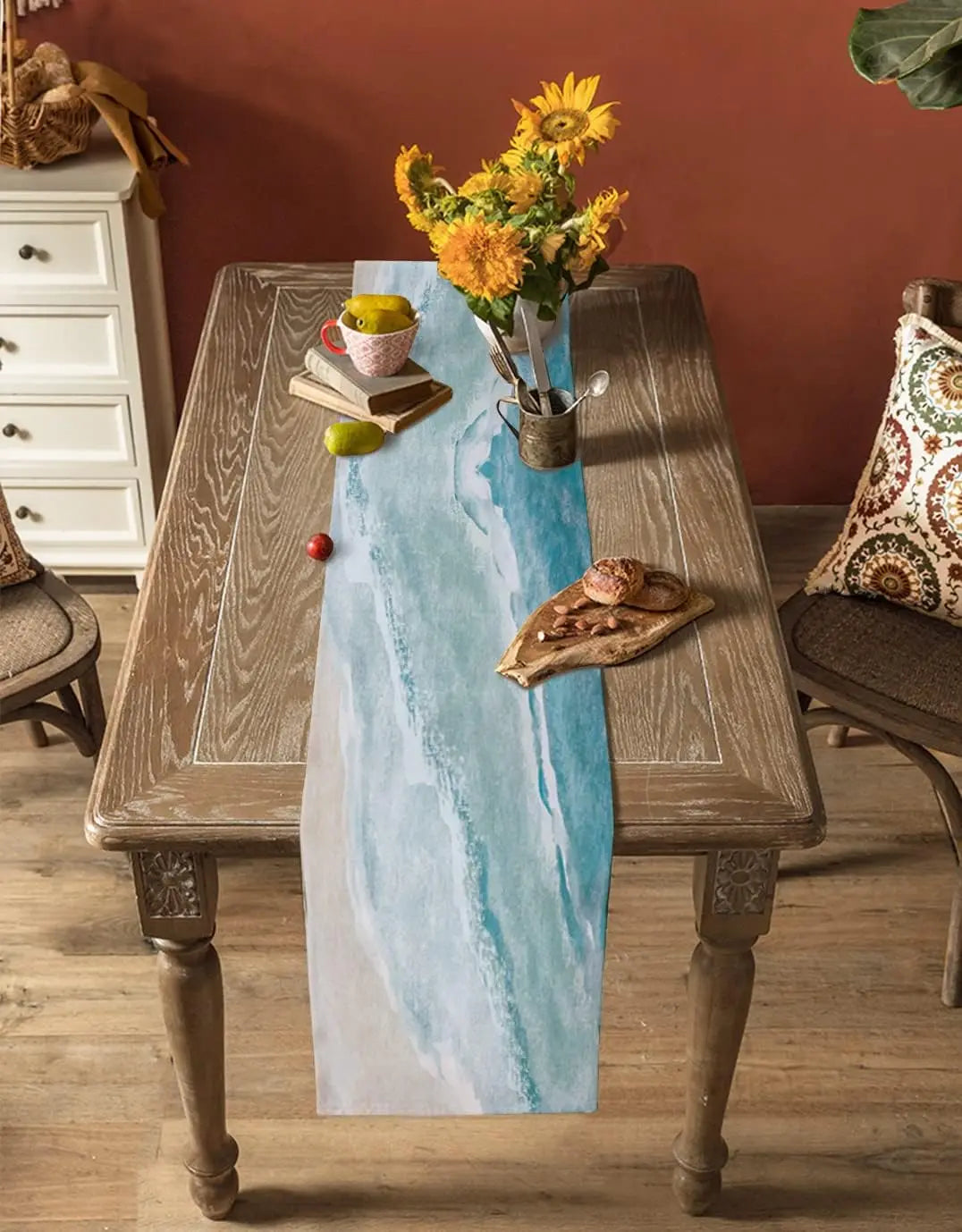 Une table en bois vintage avec un bouquet de tournesols colorés, des livres et des pommes, créant une atmosphère chaleureuse et accueillante.