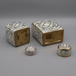 Boîtes et conteneurs décoratifs en céramique blanche et dorée avec motifs géométriques.