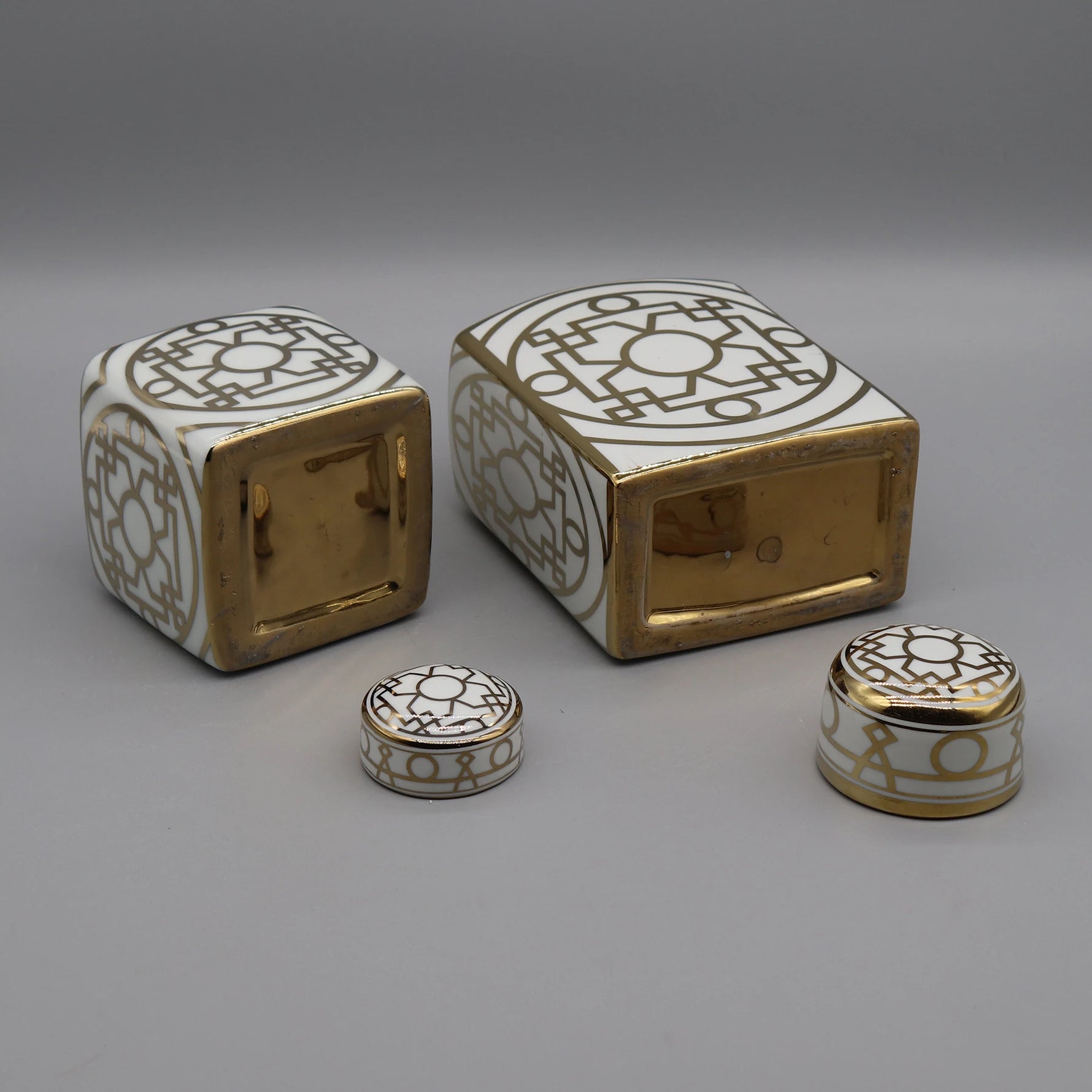 Boîtes et conteneurs décoratifs en céramique blanche et dorée avec motifs géométriques.