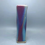 Un vase de céramique aux couleurs pourpre et bleu, avec un design moderne et épuré.