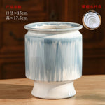 Vase en céramique gris-bleuté de forme cylindrique, avec une base ronde et une bordure lisse. Cet objet décoratif peut servir à accueillir des fleurs ou d'autres compositions florales.