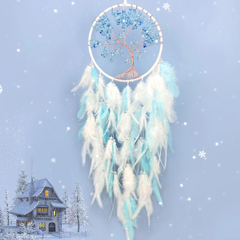 Un capteur de rêves en forme d'arbre de vie fait de pierres bleues et blanches, suspendu dans un décor hivernal avec une maison enneigée.