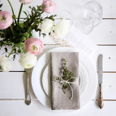 Une table élégamment dressée avec des fleurs fraîches, des verres cristallins et des couverts vintage, suggérant une atmosphère raffinée et conviviale.