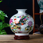 Un vase en porcelaine chinoise orné de fleurs épanouies et d'oiseaux exotiques aux couleurs vives, posé sur un socle en bois.