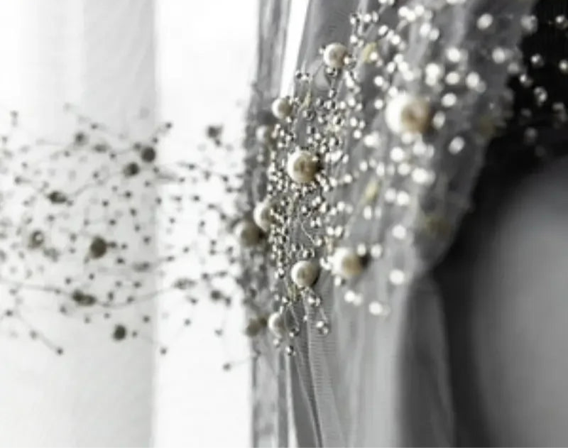 Voilage transparent gris perle décoré de perles blanches élégantes.