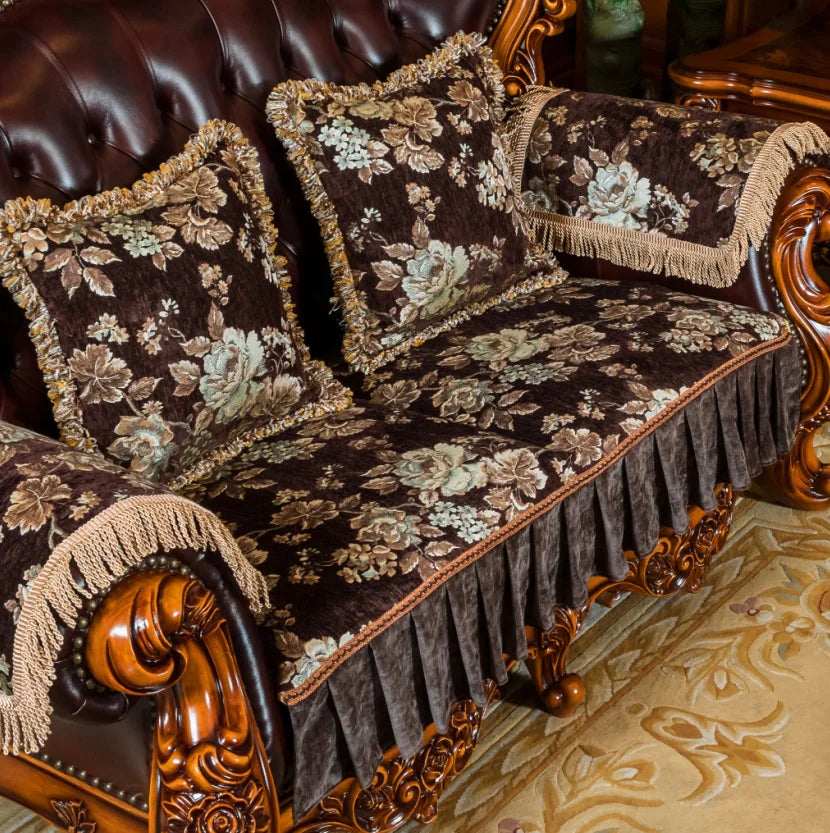 Canapé de luxe recouvert d'un tissus fleuri brun et beige avec des franges dorées et des détails sculptés en bois.